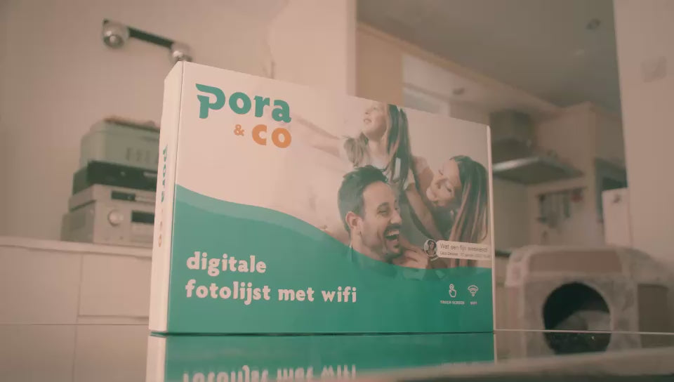 Pora & Co digitale fotolijst met Wi-Fi, getoond in de verpakking op een glazen tafel in een huiselijke omgeving.